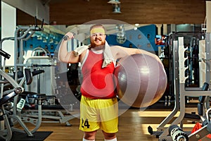Fat funny man with dumbbells in the gym.