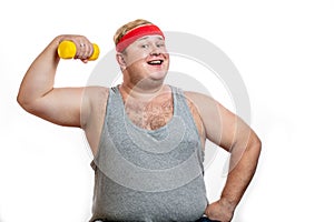 Fat funny man in red headband shows his muscles with dummbell and emotions