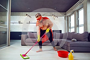 A fat, funny man in a superhero costume is cleaning the house.