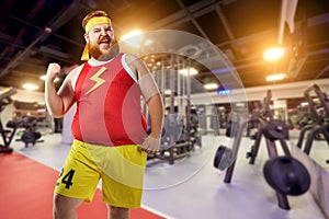 Fat funny man winner smiles in sports clothes in the gym.