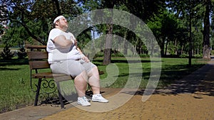 Fat girl exhausted after jogging takes minute rest on bench, combating obesity