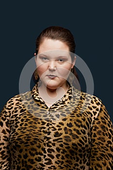 Fat girl in a leopard blouse and with big earrings. Bright makeup.