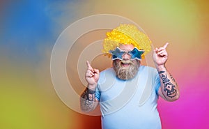 Fat happy man with beard, tattoos and sunglasses dances music on a disco