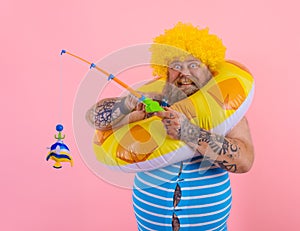 Fat happy man with wig in head plays with the fishing rod