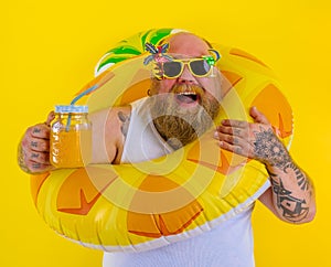 Fat happy man with wig in head is ready to swim with a donut lifesaver