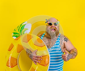 Fat happy man with wig in head is ready to swim with a donut lifesaver