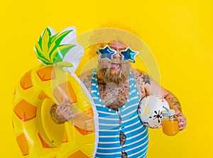 Fat happy man with wig in head is ready to swim with a donut lifesaver