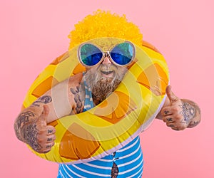 Fat happy man with wig in head is ready to swim with a donut lifesaver