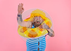 Fat happy man with wig in head is ready to swim with a donut lifesaver