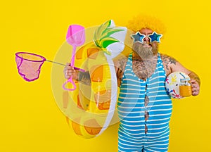 Fat happy man with wig in head is ready to swim with a donut lifesaver