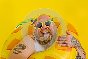 Fat happy man with wig in head is ready to swim with a donut lifesaver