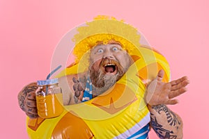 Fat happy man with wig in head is ready to swim with a donut lifesaver