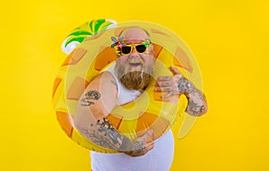 Fat happy man with wig in head is ready to swim with a donut lifesaver