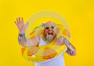 Fat happy man with wig in head is ready to swim with a donut lifesaver