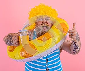 Fat happy man with wig in head is ready to swim with a donut lifesaver