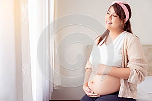 Fat Happy pregnant young asian woman holding belly and look at view with happiness smile face