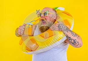 Fat hungry man with wig in head is ready to swim with a donut lifesaver