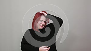 Fat lady in black sweater happy woman smiles and touches head, hair with hands