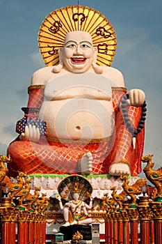 Fat laughing Buddha over blue sky