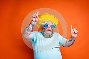 Fat man with beard, tattoos and sunglasses dances music on a disco