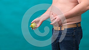Fat man with a big belly holds a green apple in his hand. The concept of healthy eating and losing weight, diet.