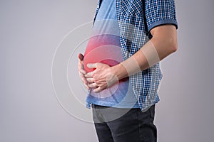 Fat man with bloating and abdominal pain, overweight male body on gray background photo