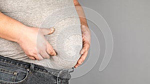 Fat man, checking his weight, on a gray background