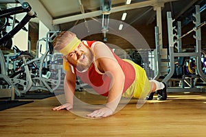 A fat man does push-ups from the floor in the gym.