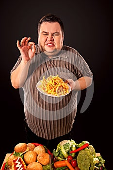 Fat man eating fast food french fries for overweight person.