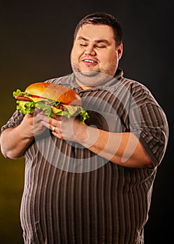 Fat man eating fast food hamberger. Breakfast for overweight person.