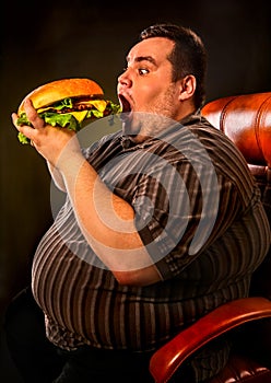 Fat man eating fast food hamberger. Breakfast for overweight person.