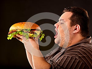 Fat man eating fast food hamberger. Breakfast for overweight person.