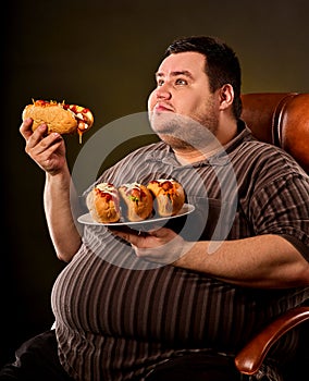Fat man eating fast food hot dog. Breakfast for overweight person.