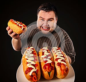 Fat man eating fast food hot dog. Breakfast for overweight person.