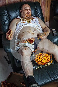 Fat man eating junk food and watching television