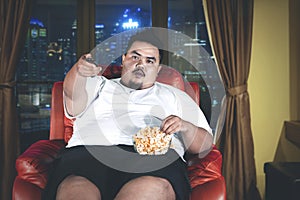 Fat man eats popcorn during watch television