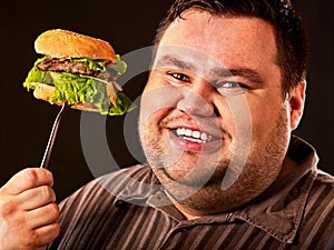 Fat man face eats burger on fork