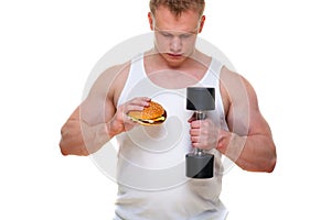 Fat man with a hamburger holds dumbbells isolated on white. The concept of choosing between harmful food and a healthy