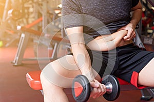 Fat man holding dumbbell and excessive fat belly, overweight fatty belly at fitness gym. Diet lifestyle, weight loss, stomach