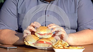 Fat man holding hamburger, unhealthy food, calories and diet, obesity problem