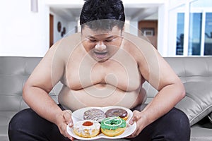 Fat man holding a plate of donuts