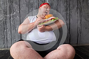 Fat man holds a sandwich like a child