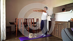 Fat man and pomeranian dog doing gymnastics at home. Doing fitness with your dog. Overweight guy and funny dog doing yoga exercise