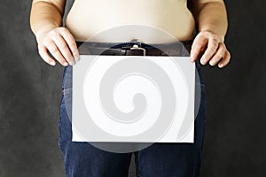 A fat man s belly holds a sheet of white paper clean, or with the inscription steam to lose weight - close-up