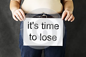 A fat man s belly holds a sheet of white paper clean, or with the inscription steam to lose weight - close-up