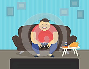 Fat man sitting at home on the sofa playing video games and eating