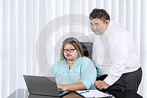 Fat man supervising her female employee working