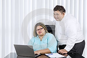 Fat man supervising her female worker working