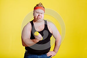 Fat man try to lift small yellow dambbell