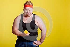 Fat man try to lift small yellow dambbell